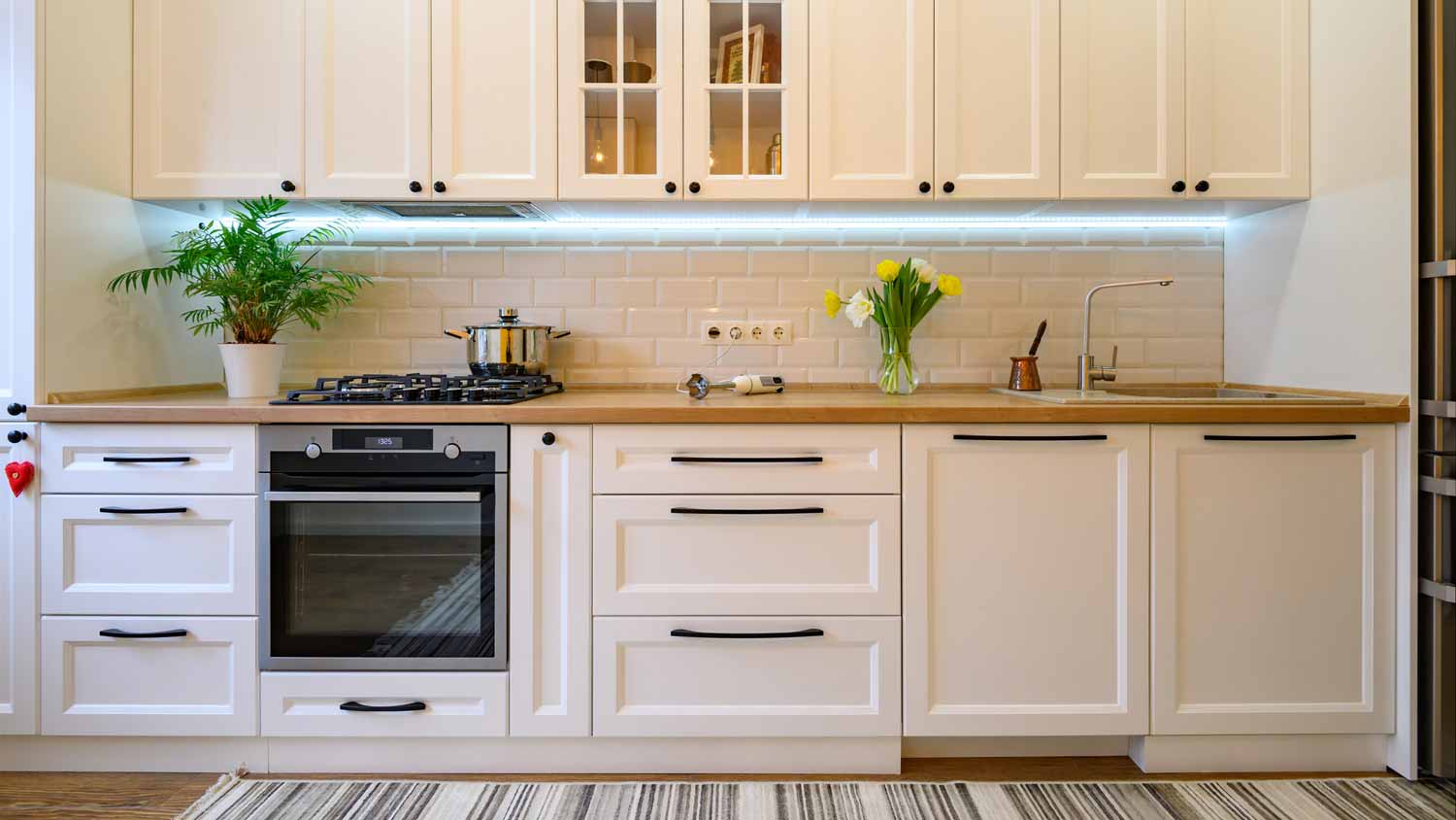 A kitchen with white cabinets and LED lights