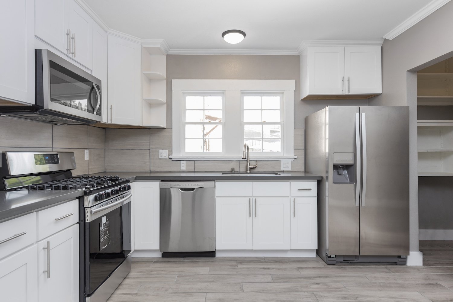 A remodeled kitchen with white cabinets and stainless steel appliances