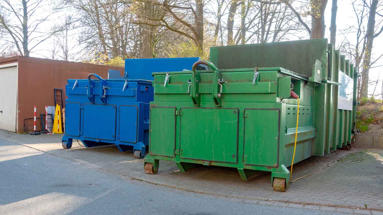 Two compacting dumpsters sitting in a parking lot 