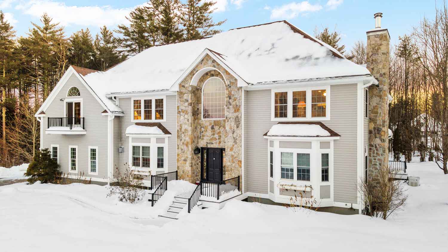 Large two-story house with chimney is covered with snow