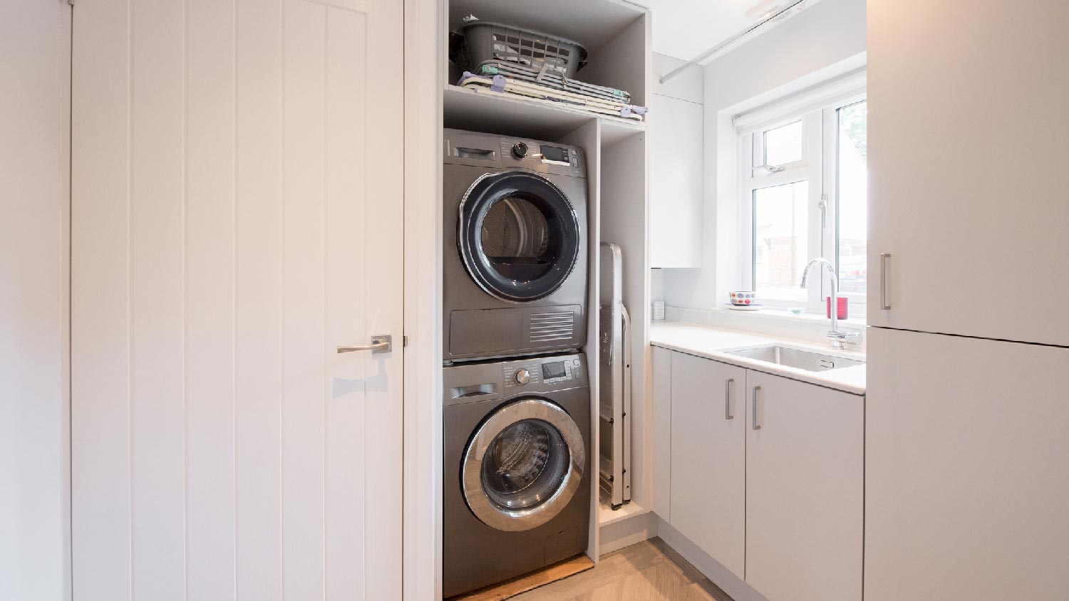 A laundry room with a dryer stacked on top of a washing machine