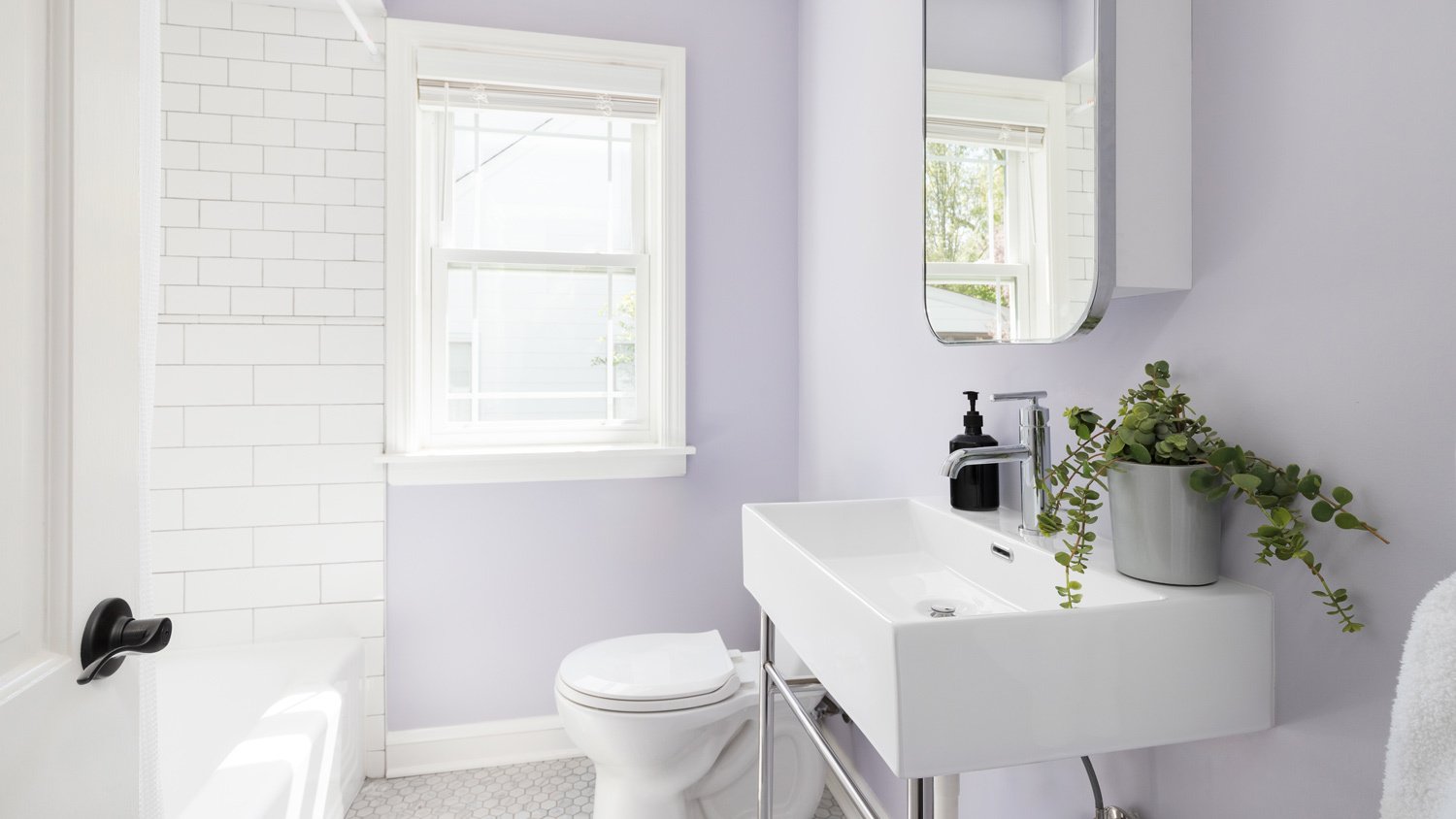 A bathroom with purple walls and white subway tile shower
