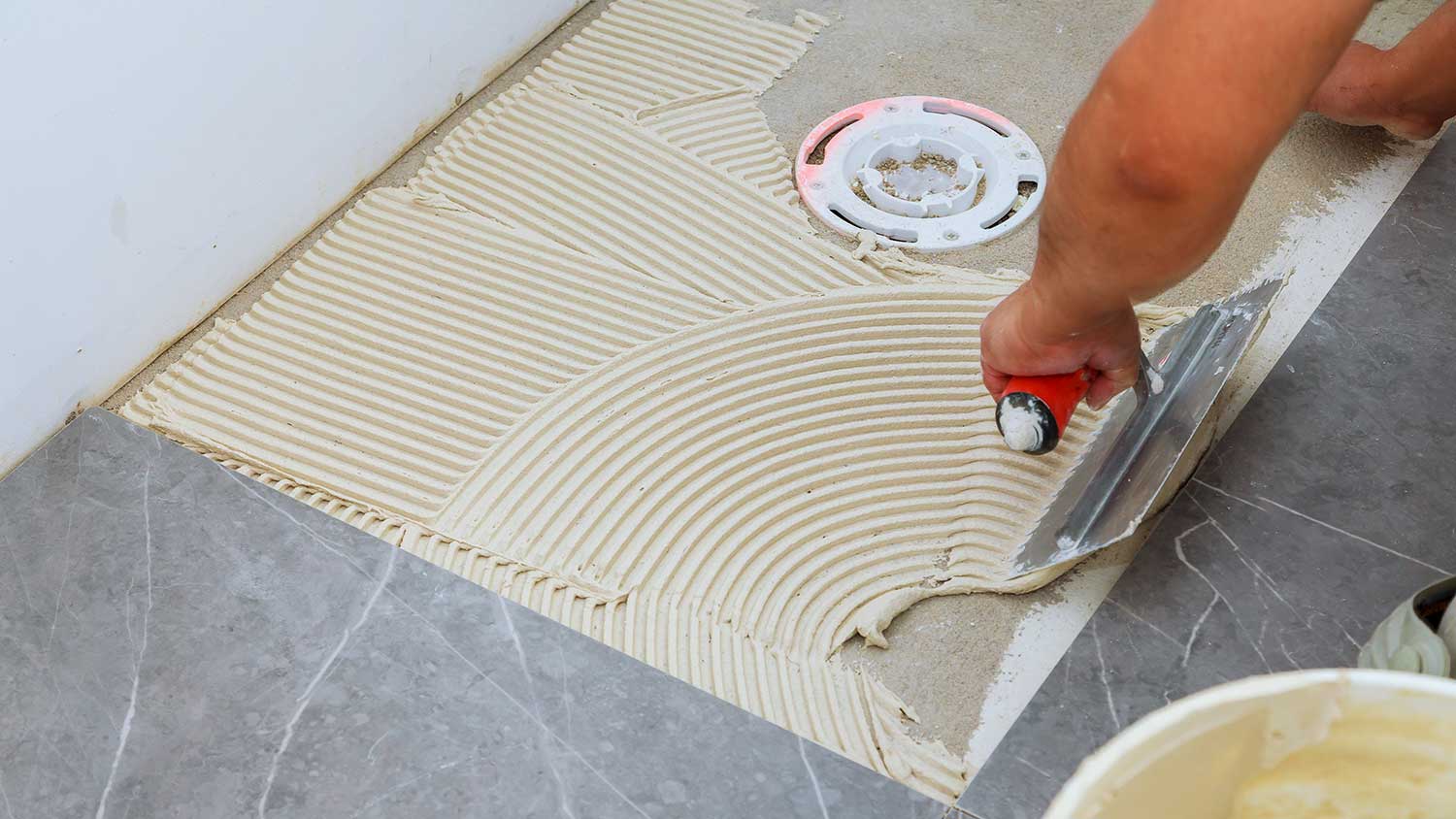 Worker laying mortar with a trowel on a bathroom floor