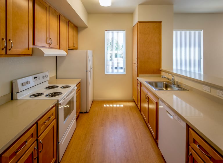 kitchen with wood cabinets, wood floor, linoleum countertop, and white appliances
