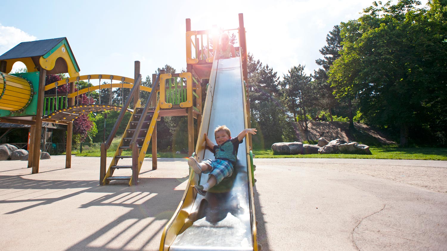 A little boy sliding down a playground’s slide