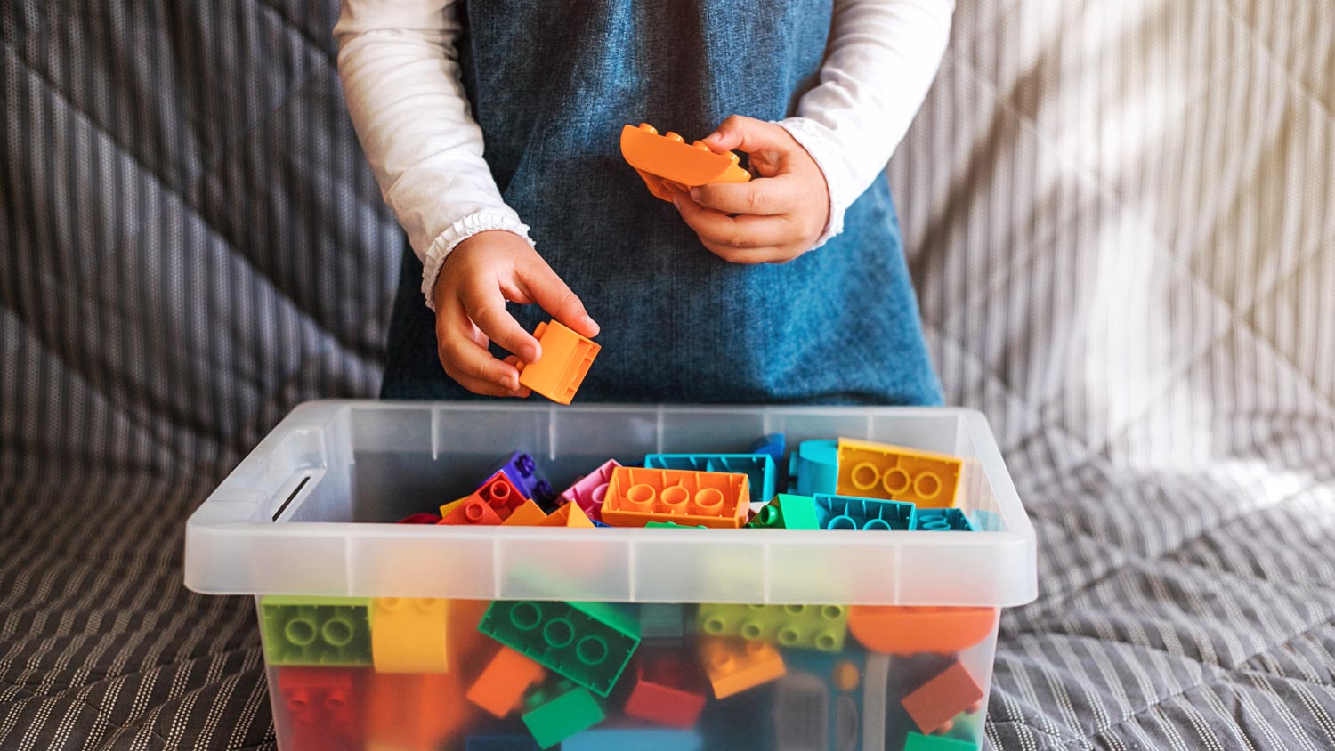 A little girl cleaning up her toy box