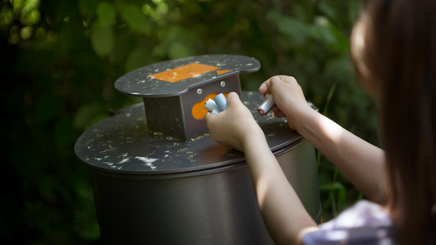 A little girl disposing batteries on a designated bin