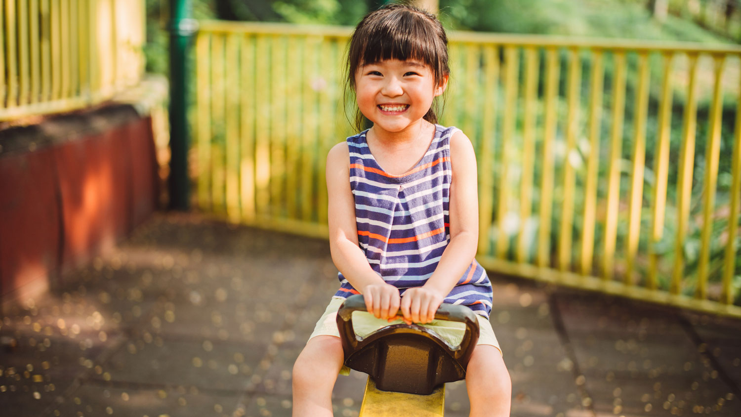 A little girl smiling while playing seesaw