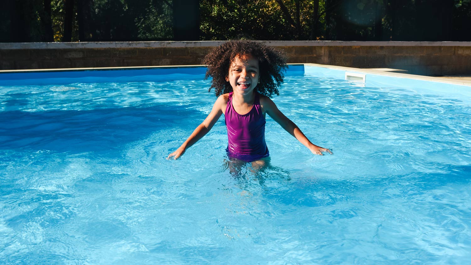 girl in a purple swimsuit swims in the pool