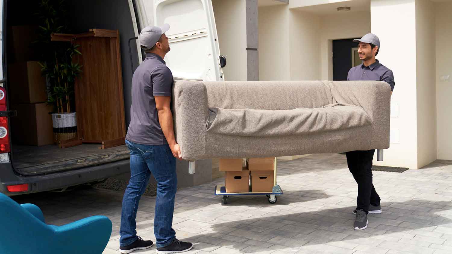 Junk removal service workers loading old sofa into a van