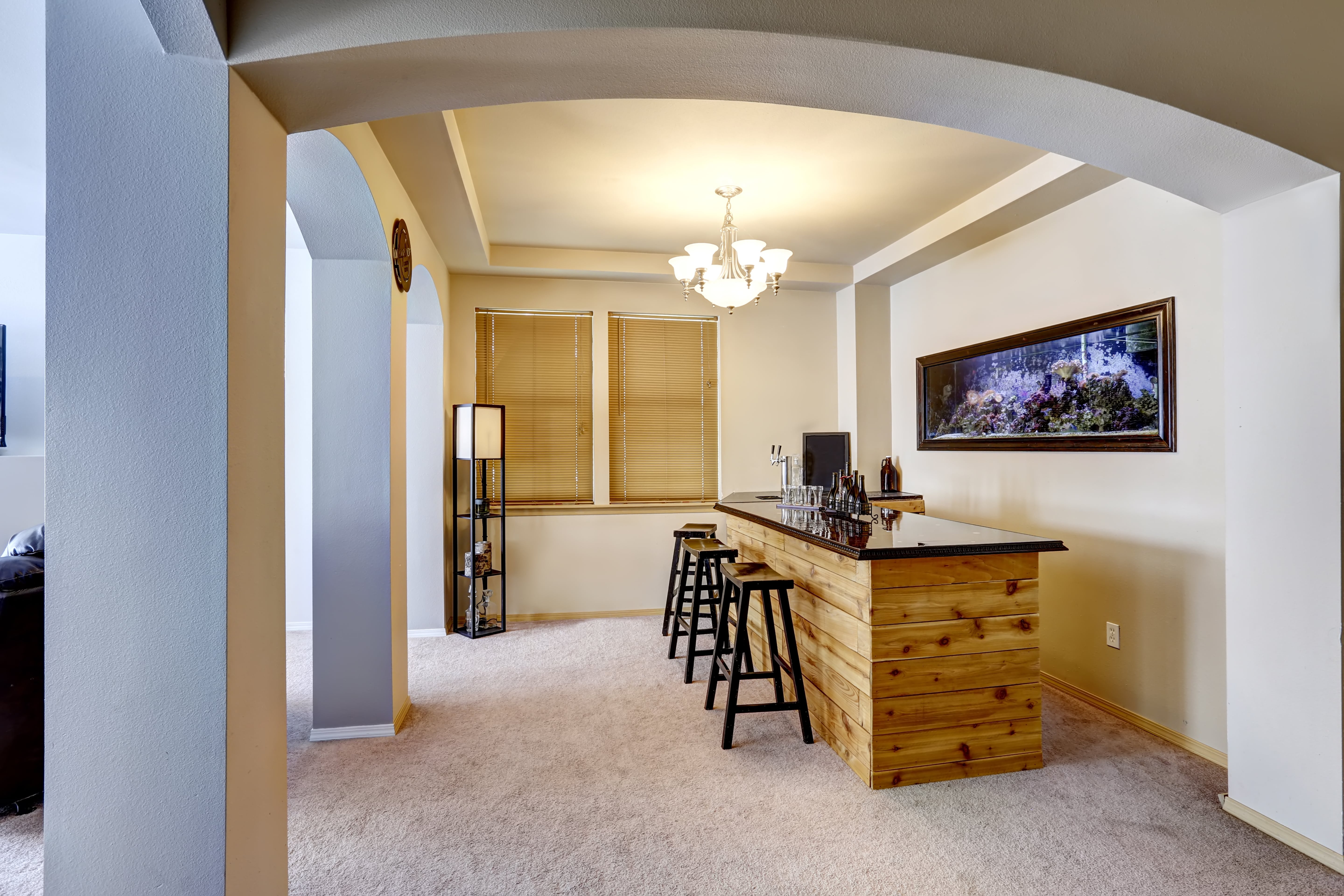 A loft room with carpeted floors and a small bar with an aquarium behind it