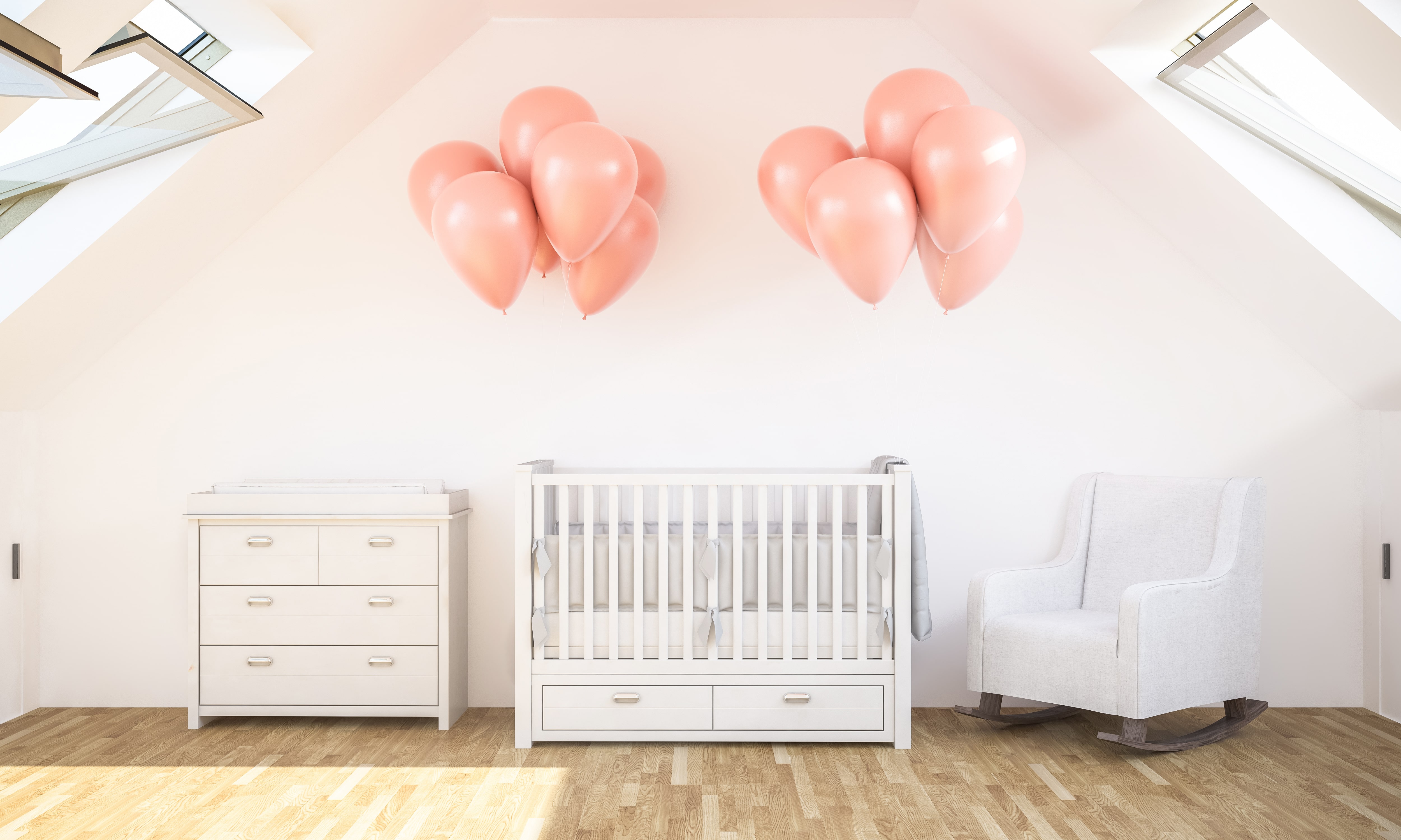 A front facing image of a crib in a nursery with pink balloons tied to either side