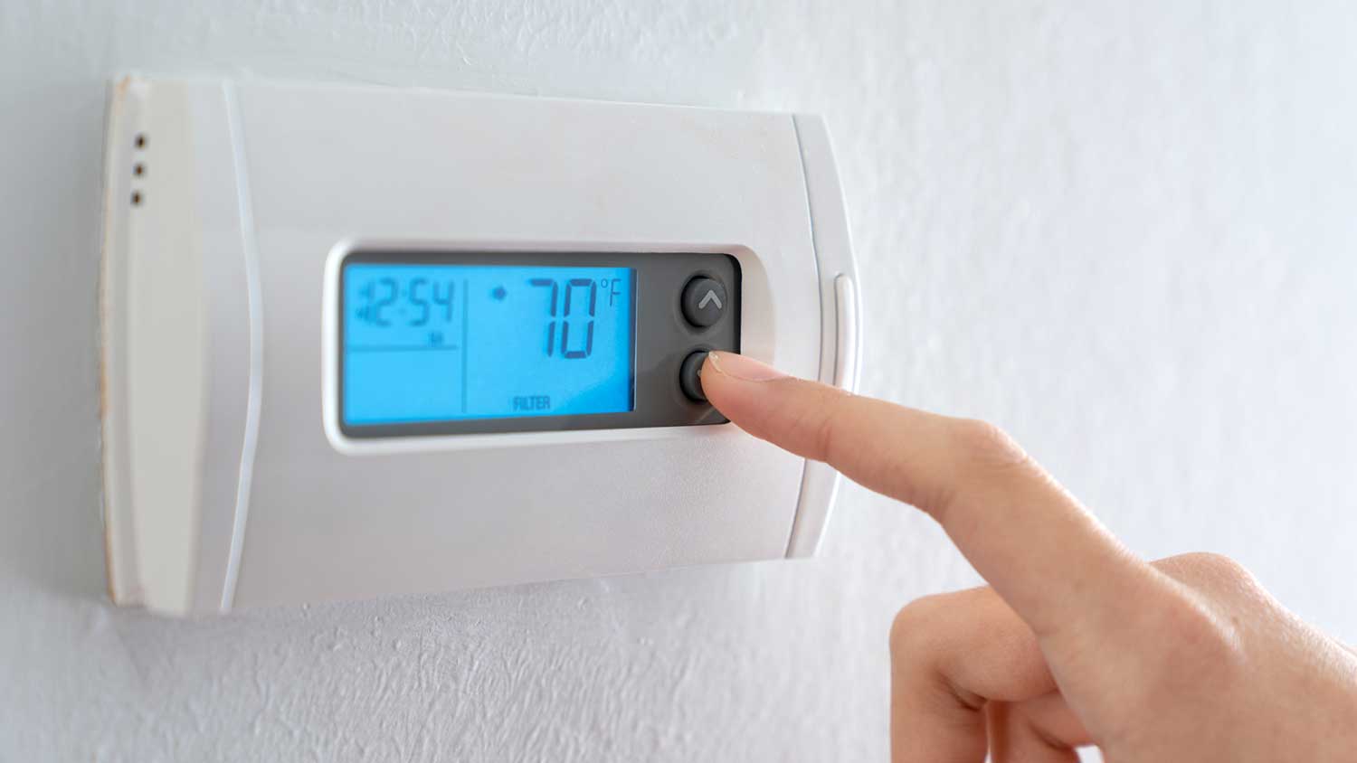 A person lowering the temperature on a thermostat