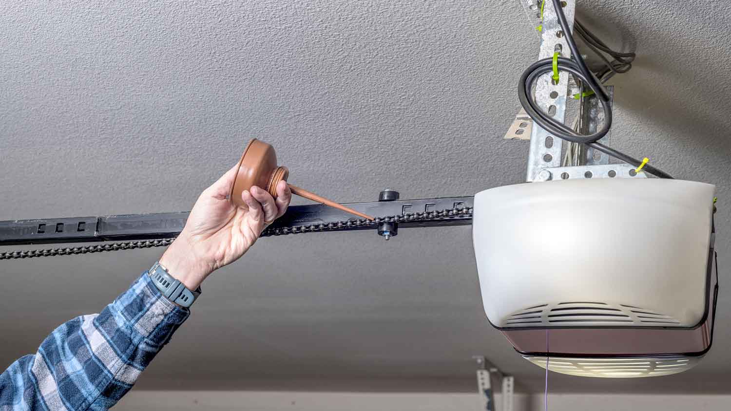 Handyperson lubricating automatic garage door belt