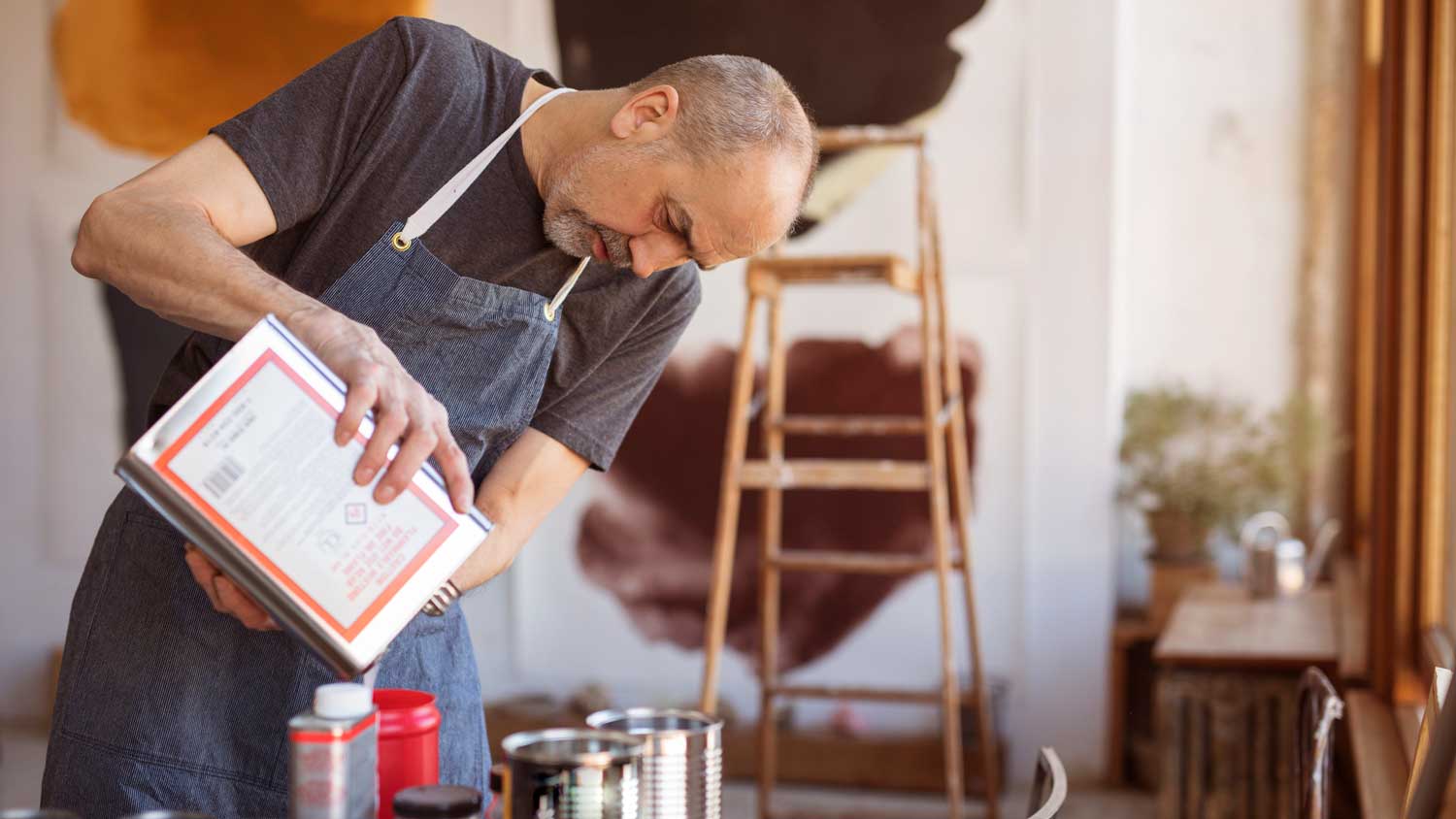  A man adding additive to a paint bucket