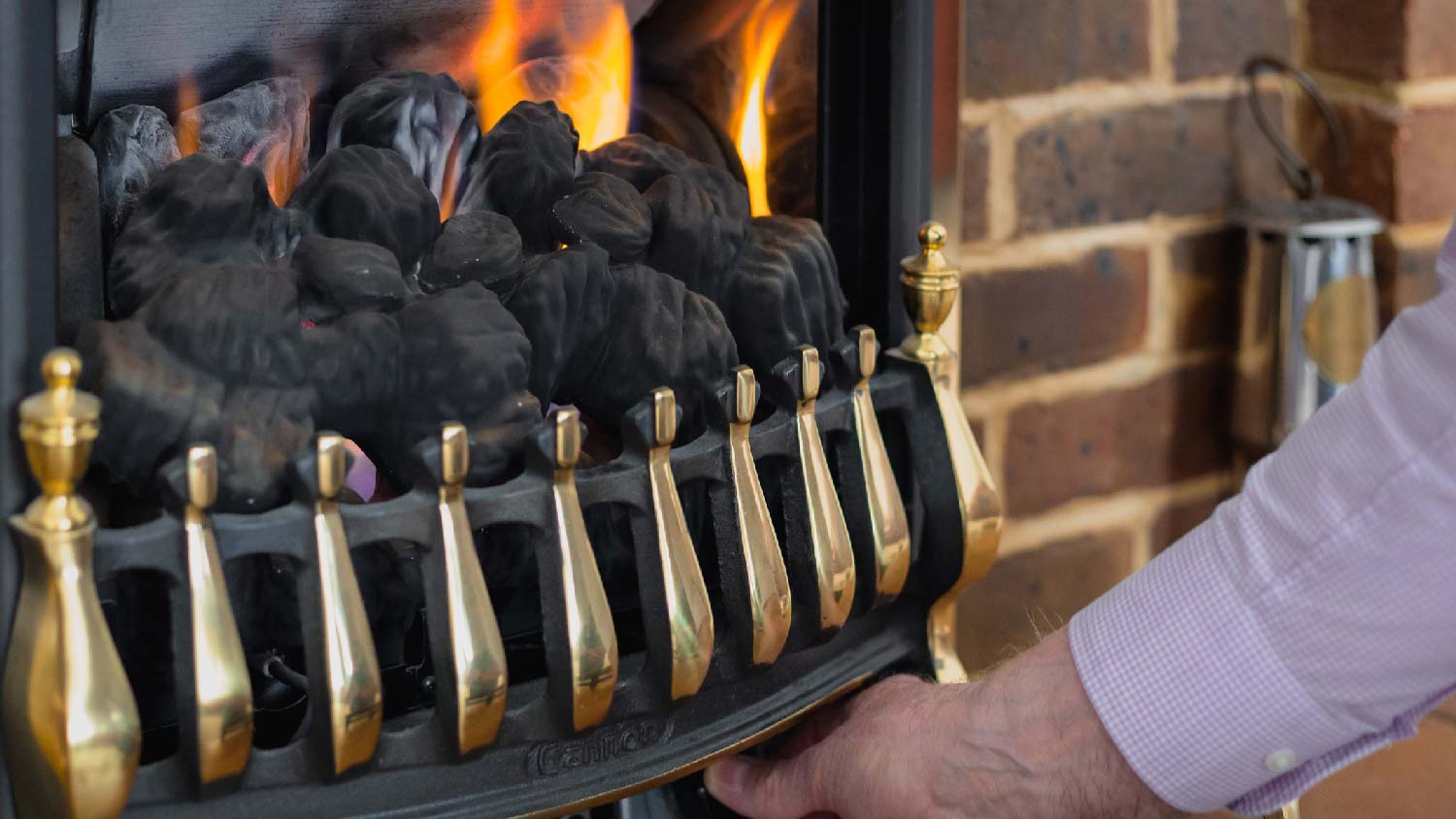 A man adjusting the heat on a gas fireplace