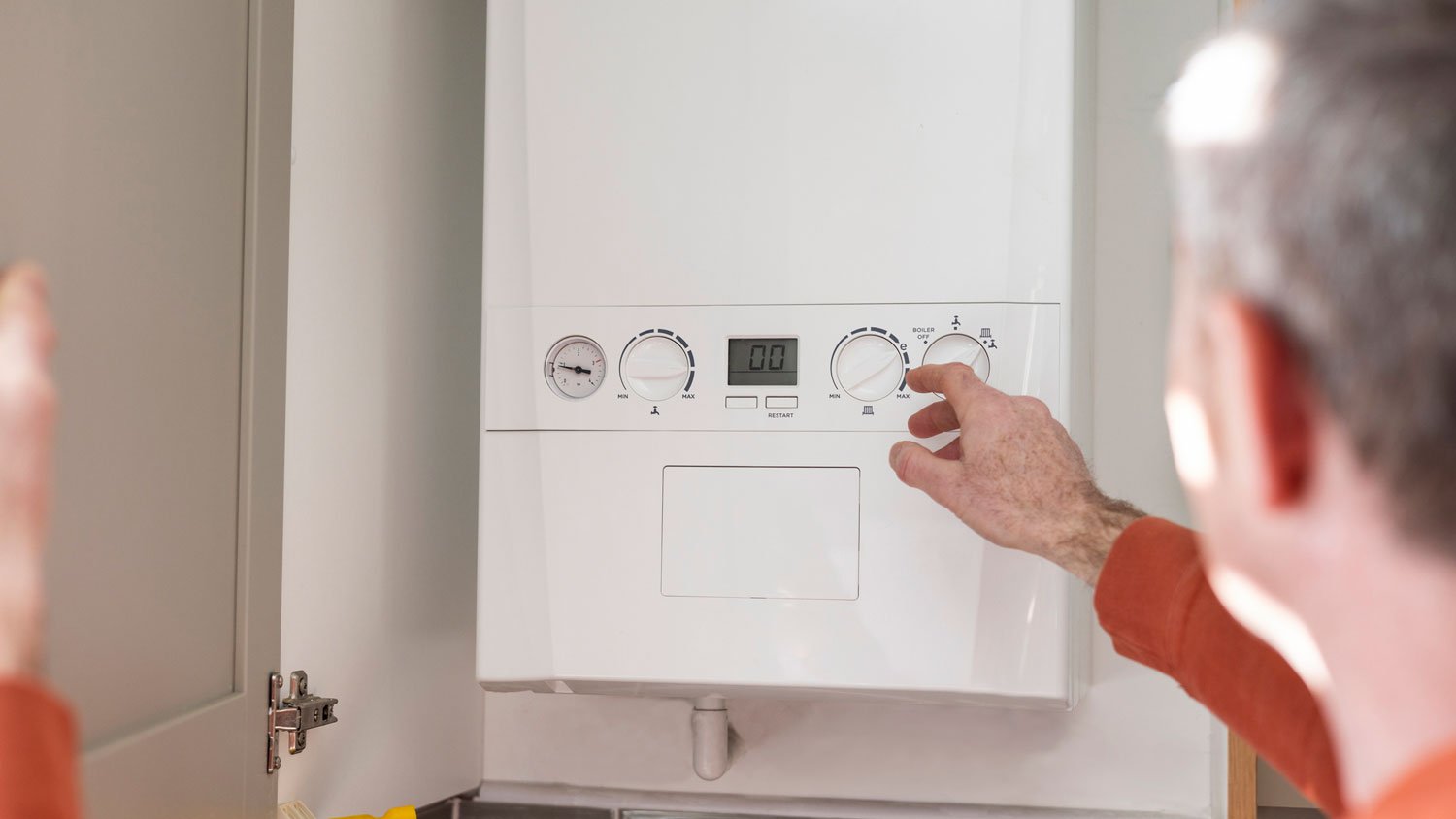 A man adjusting a tankless water heater