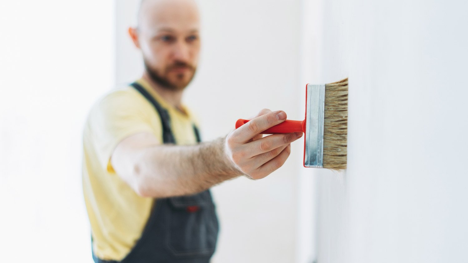 A man applying paint primer on wall