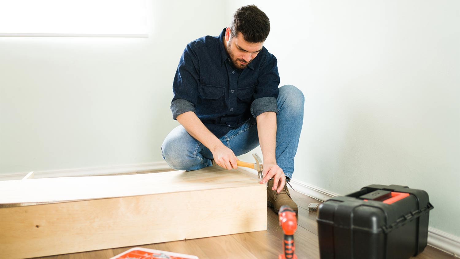 man hammering wood to make bookshelf