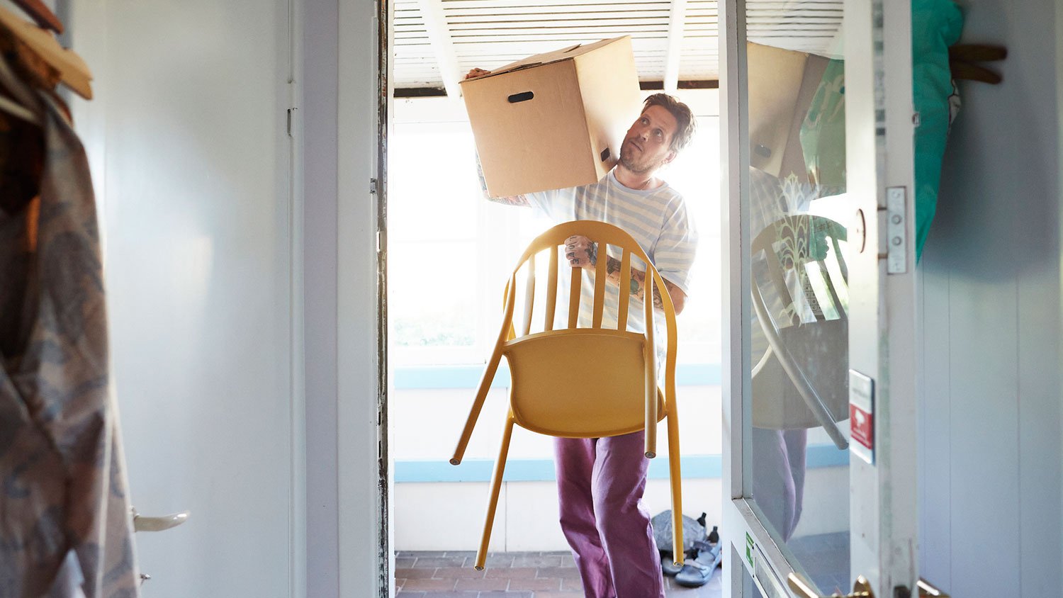 Man moving outdoor furniture inside