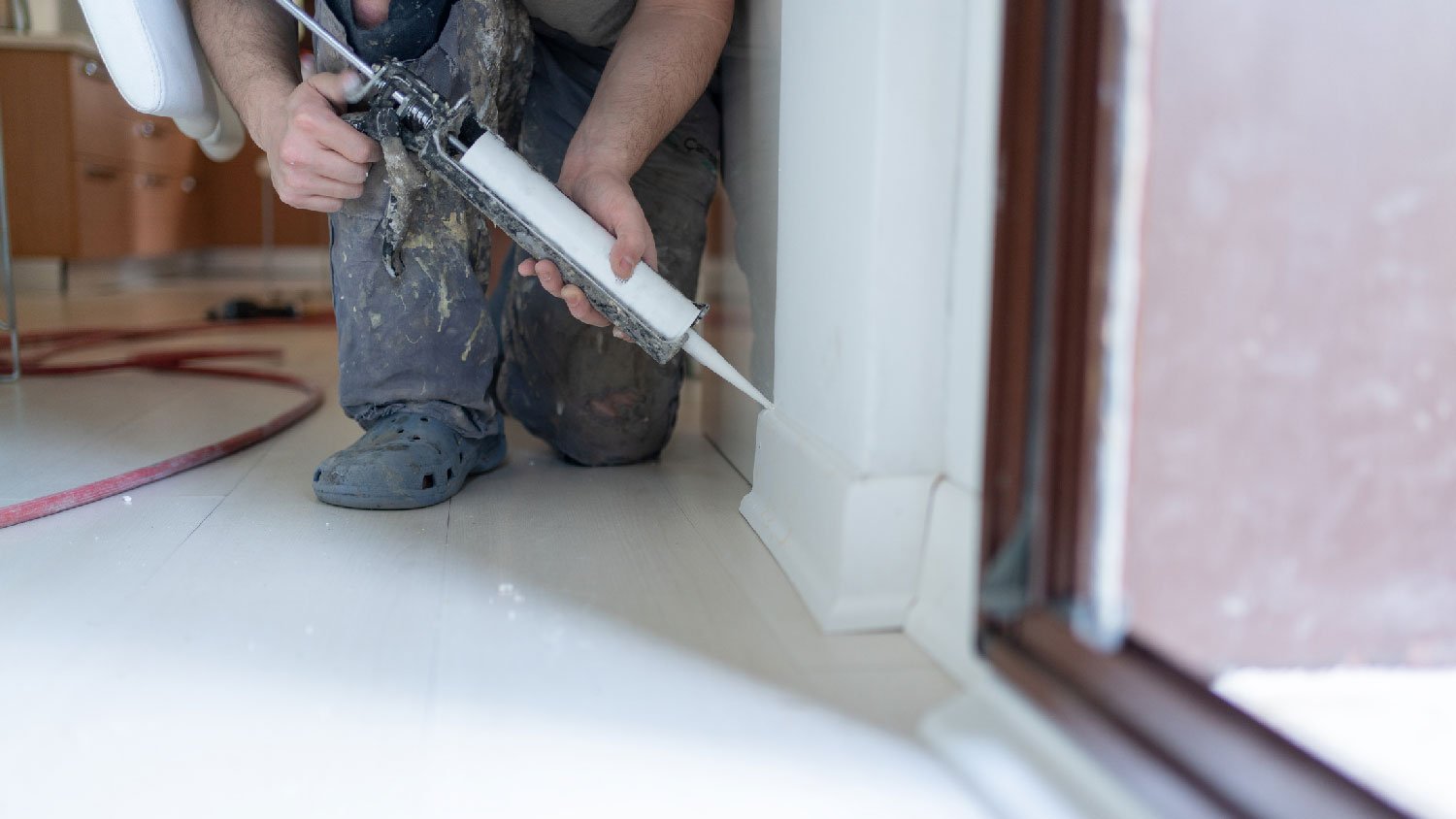 A man caulking a baseboard 