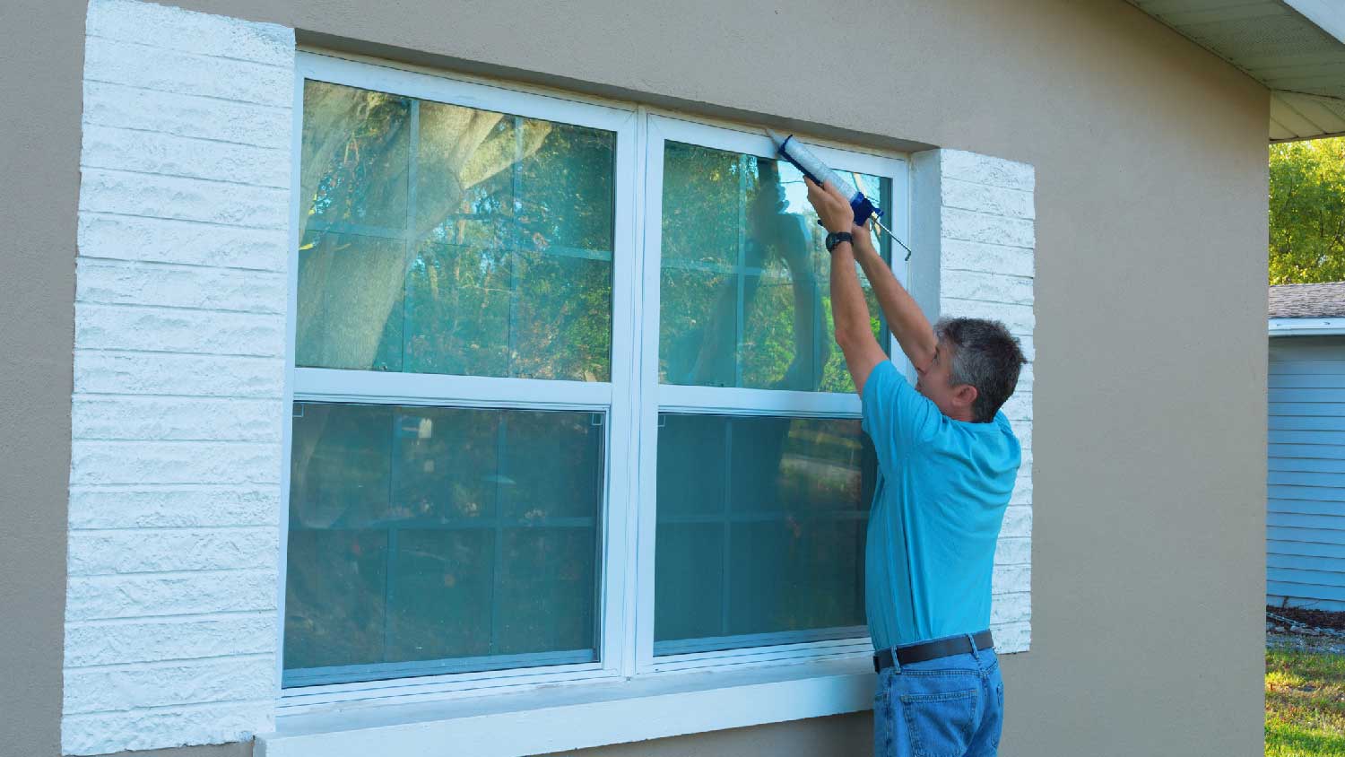 A man caulking storm windows