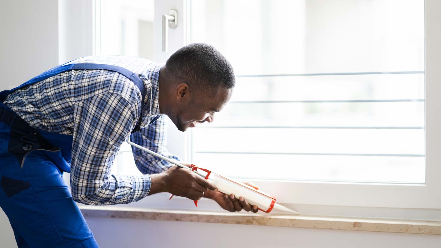 A man caulking a window