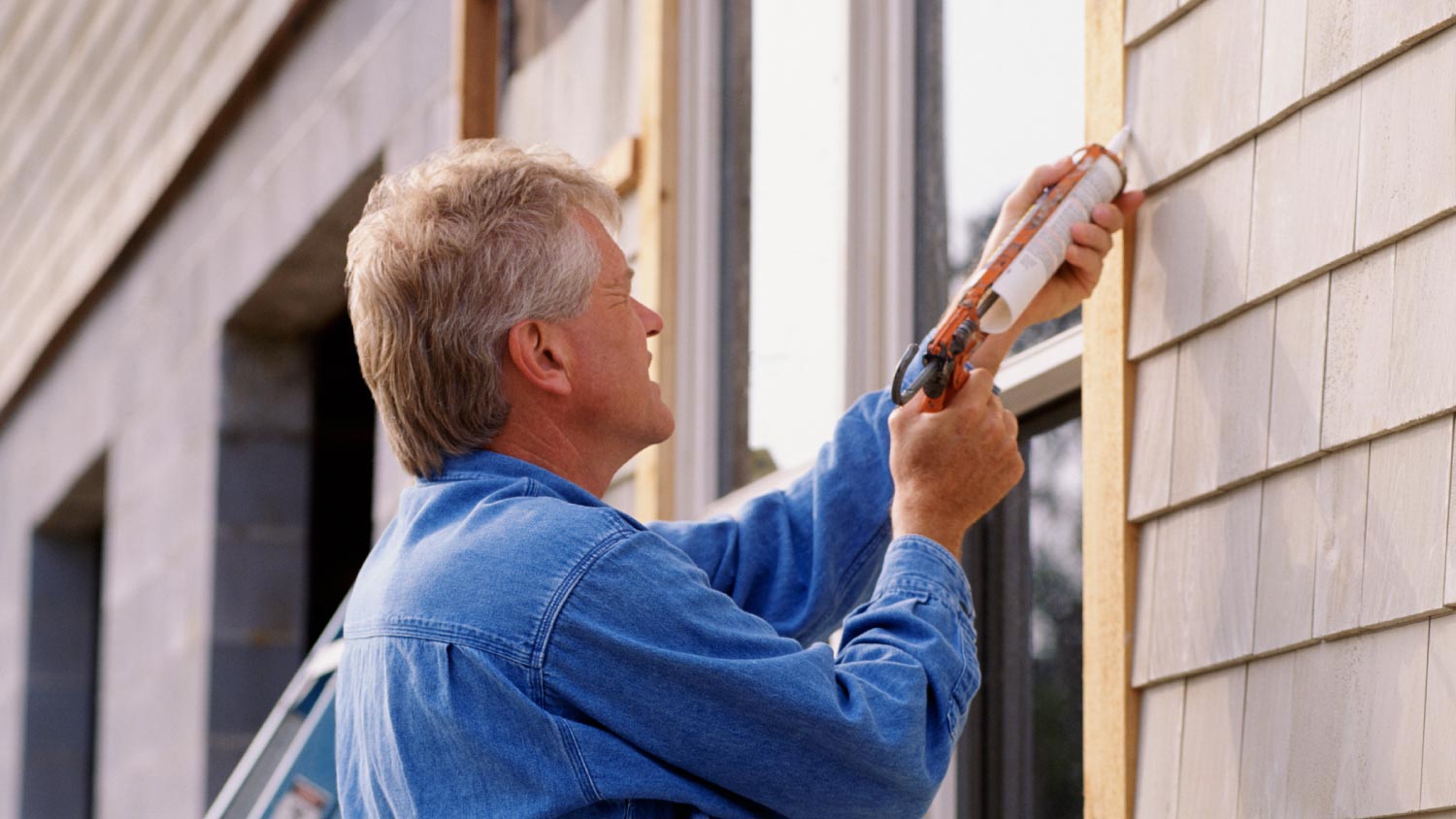 A man caulking window