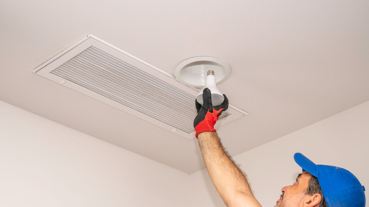 A man changing a bulb in a can lighting