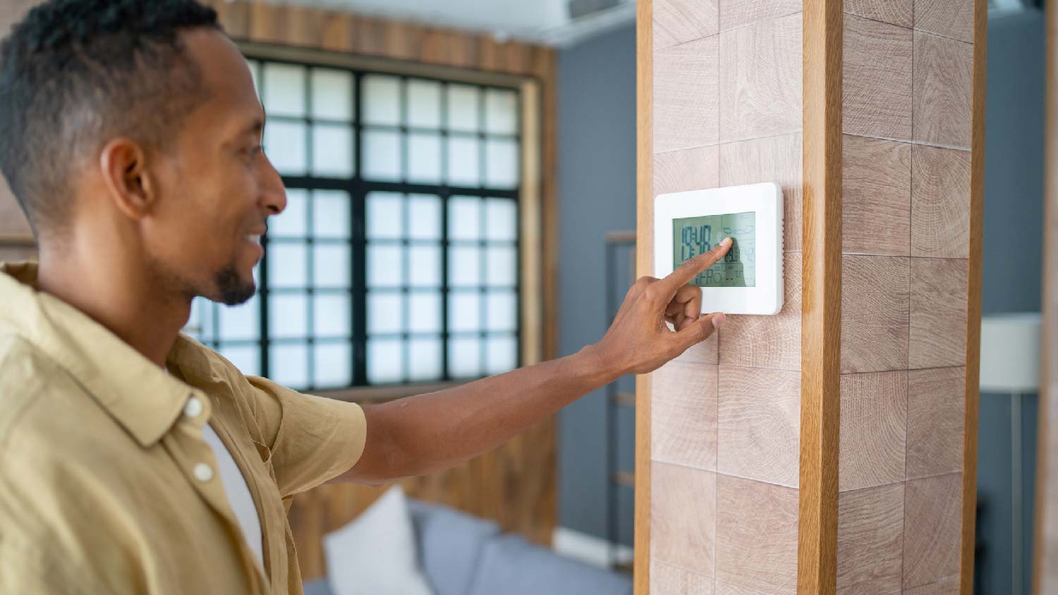 A man changing temperature via a smart thermostat