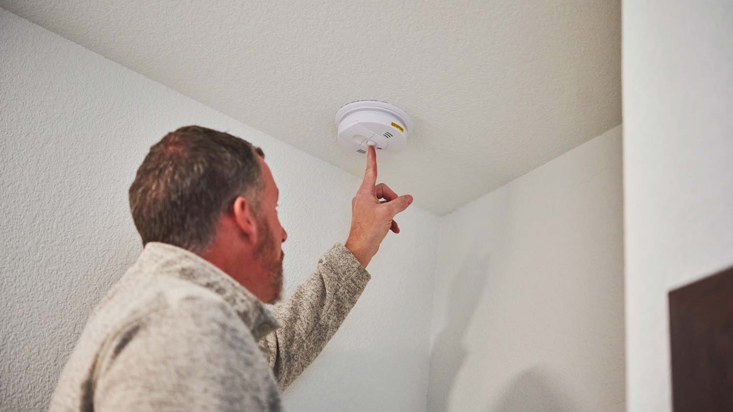 A man checking the working condition of a smoke alarm