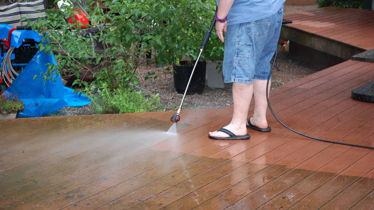 man rinsing off deck with pressure washer