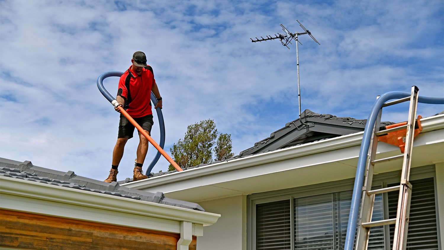 A man cleans gutters on a house