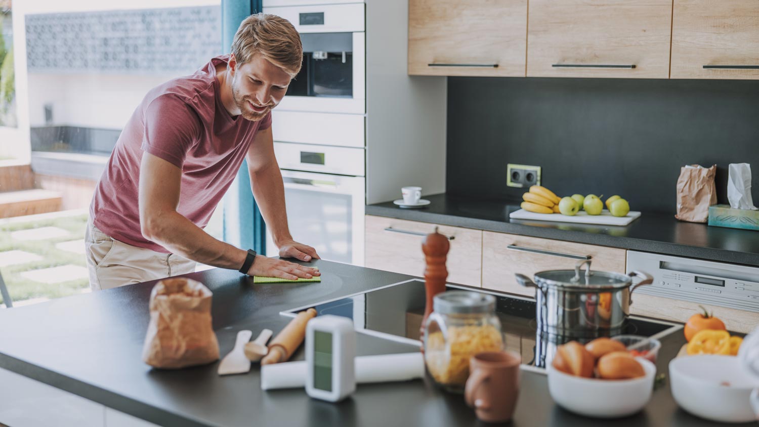 A man cleaning a kitchen countertop with a cloth