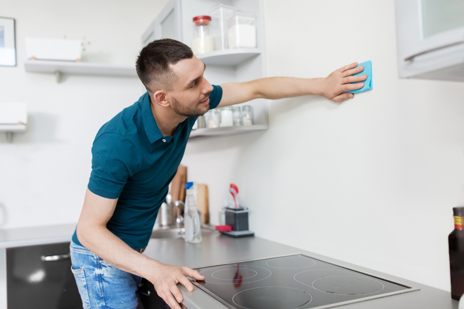 Man cleaning kitchen walls with a cloth