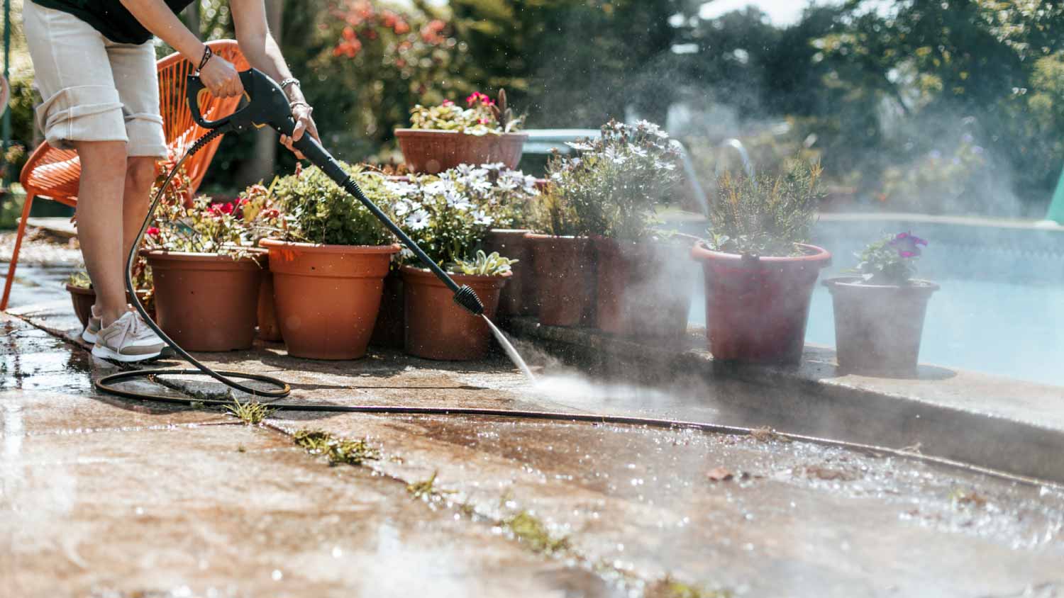 Man cleaning the poolside with high pressure water