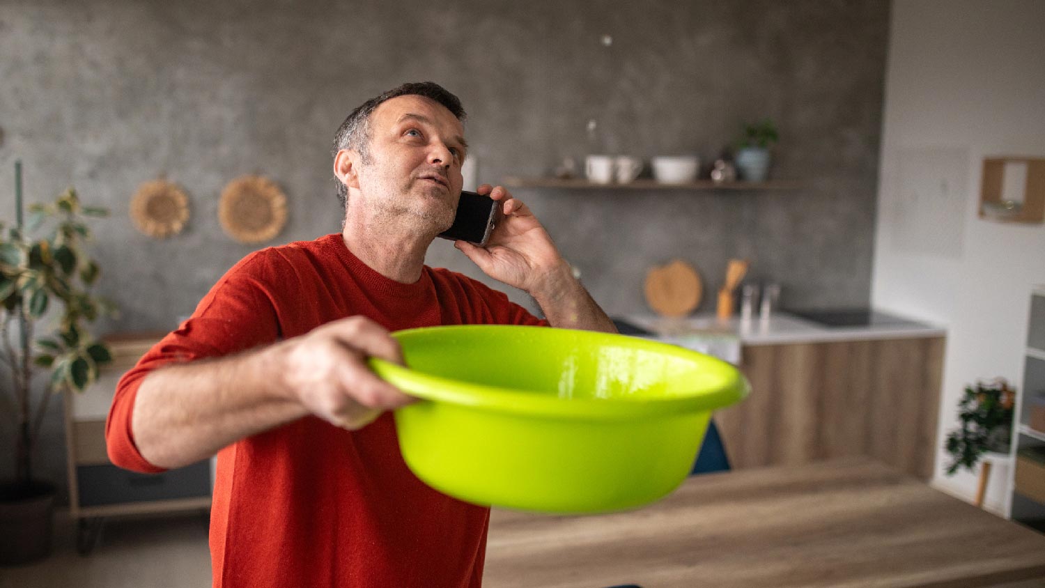 A man collecting water from a leaking roof