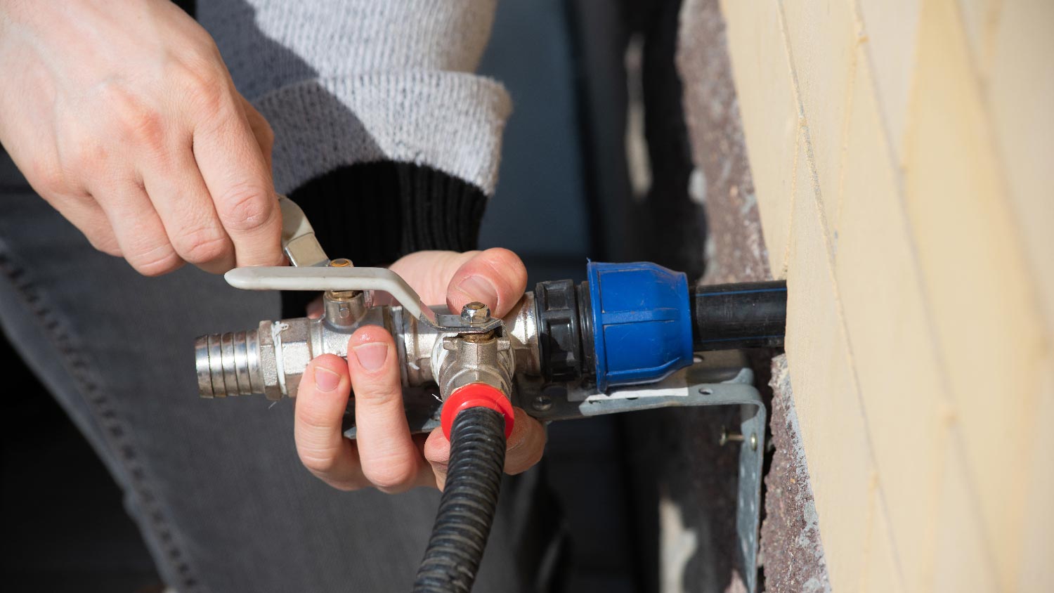 A man connecting the water pressure gauge to a hose bib