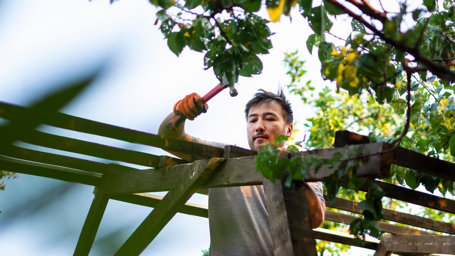 A man constructing a wooden pergola