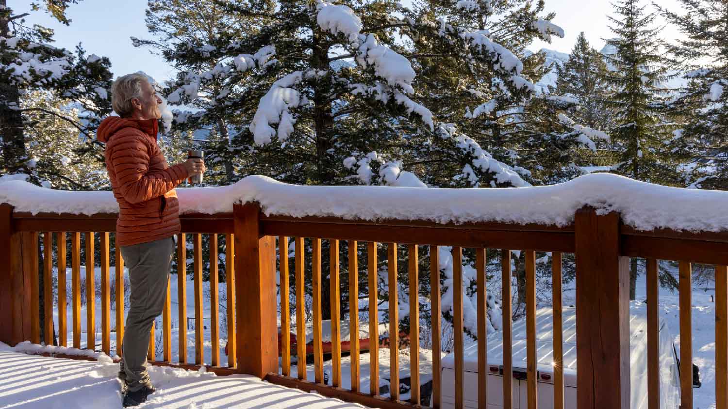 A man enjoying his morning coffee on the snow covered deck
