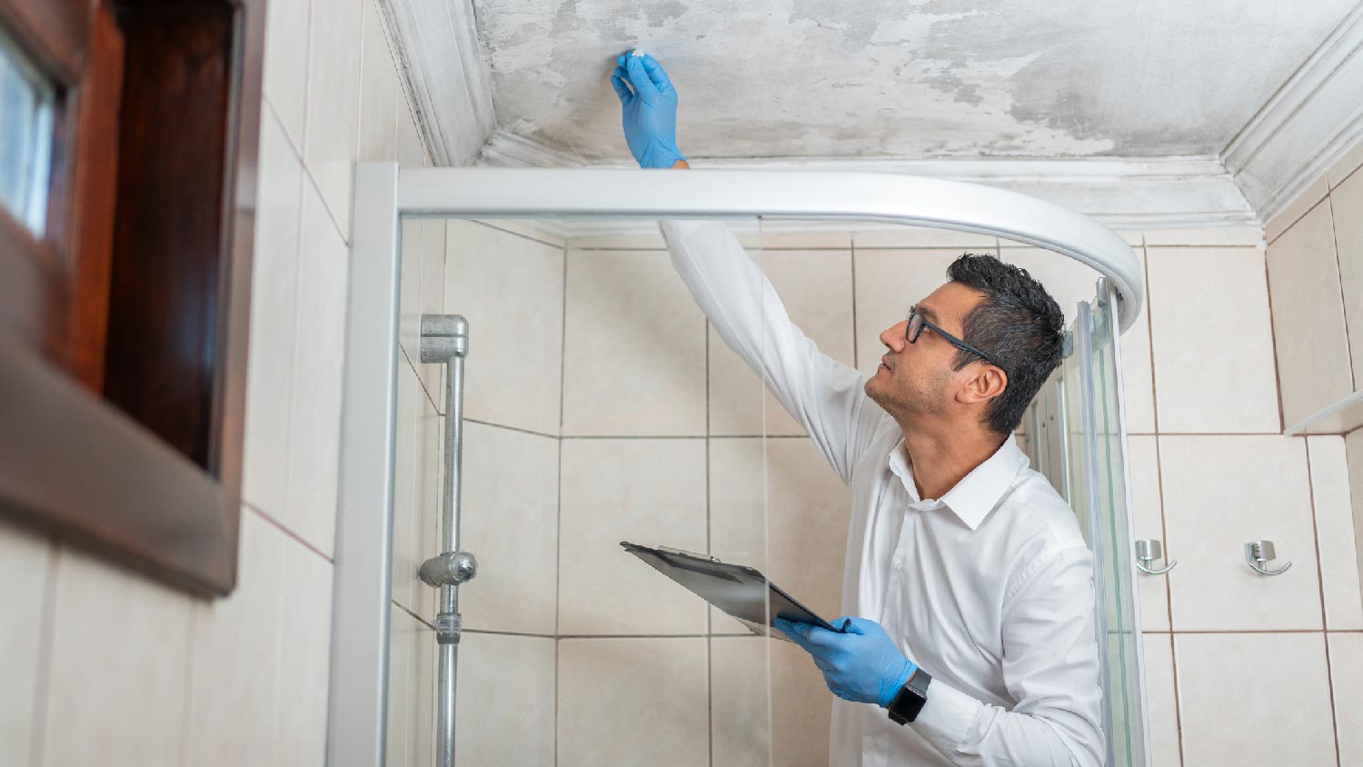 A man examining fungi on the ceiling