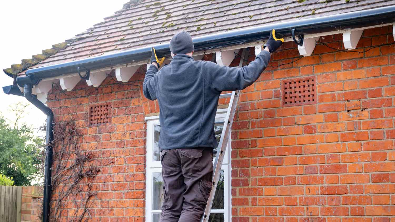  man on ladder fixing gutter 