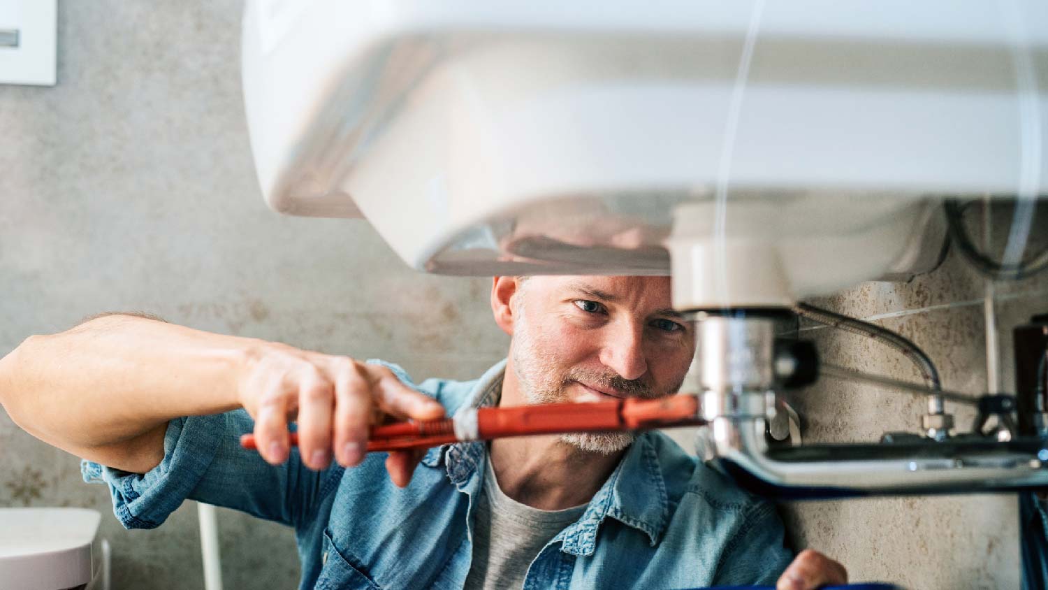 A man fixing a water leak in the bathroom sink