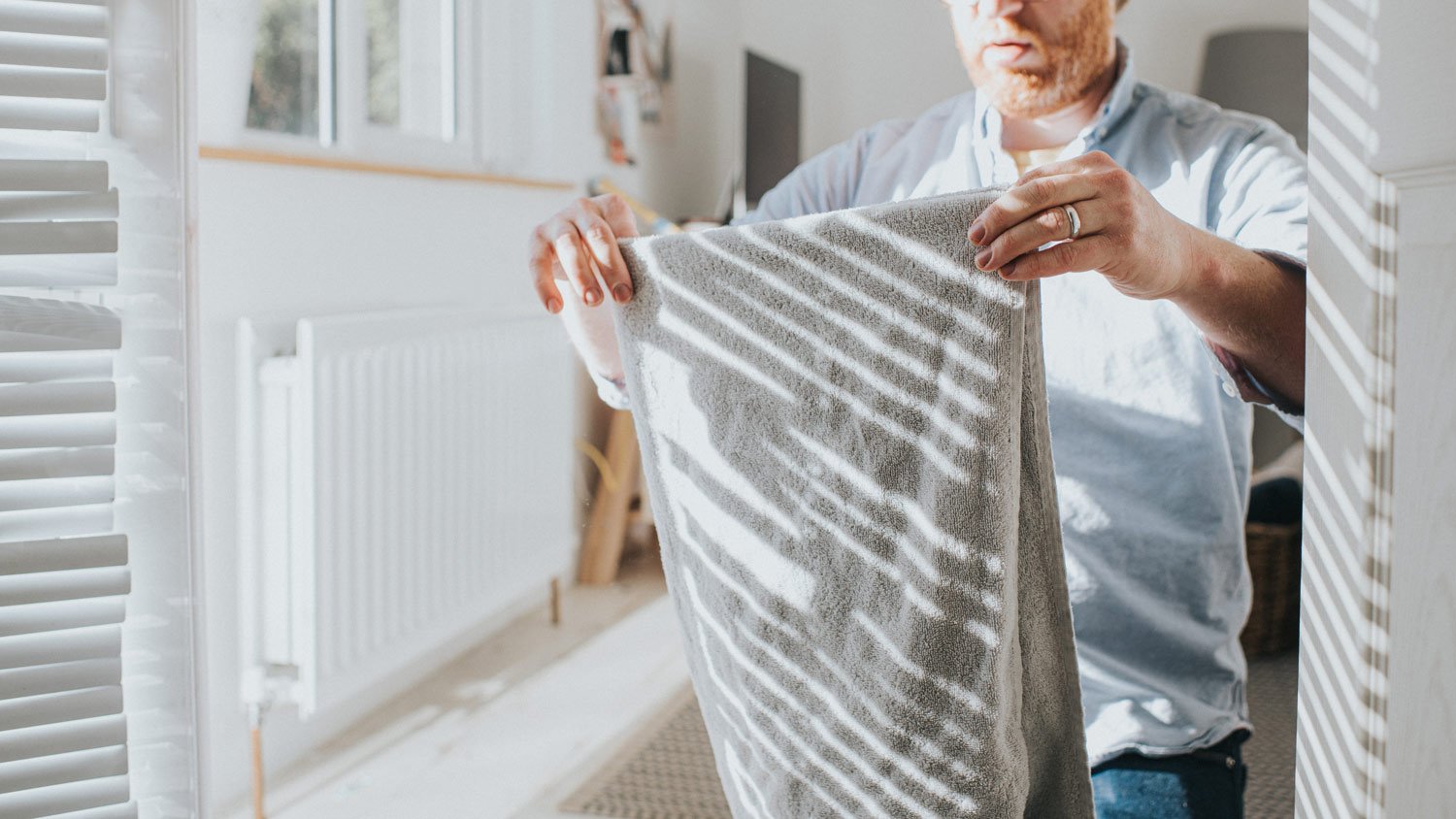 A man folding towel in a sunny room