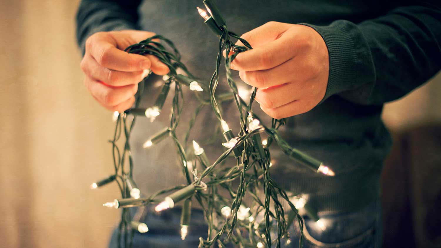 Closeup of a man holding a Christmas light strand