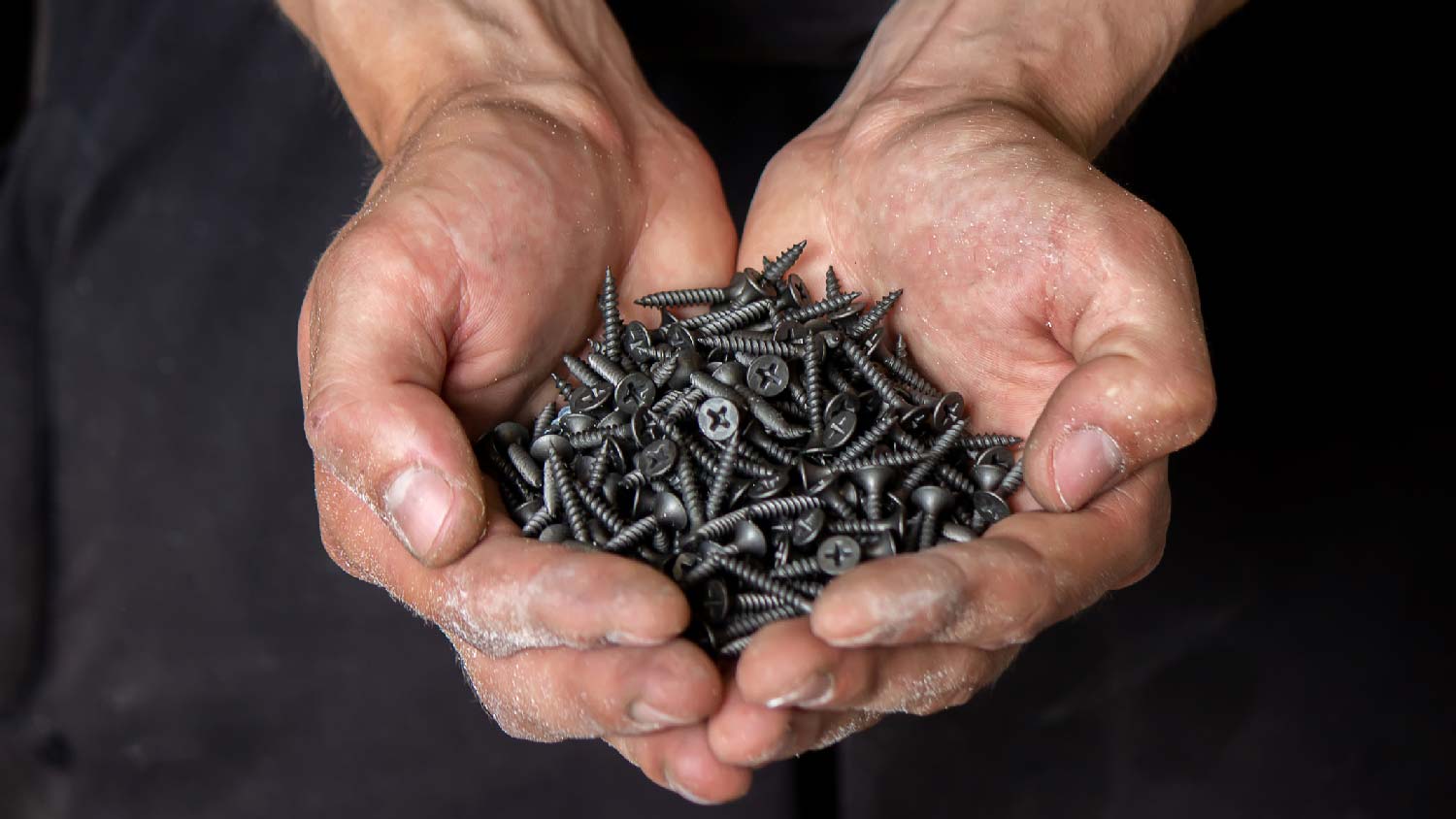 A man holding a bunch of fine drywall screws