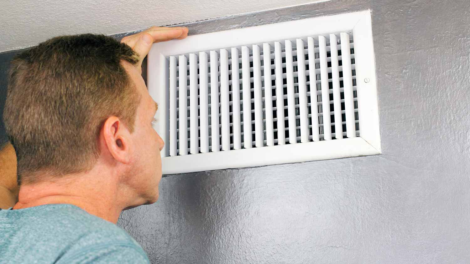 A man inspecting an air duct