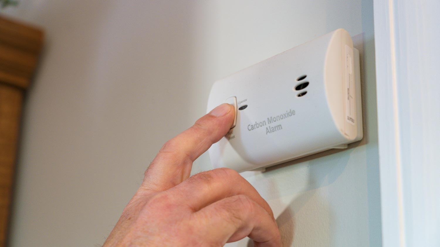  A man inspecting a carbon monoxide detector 