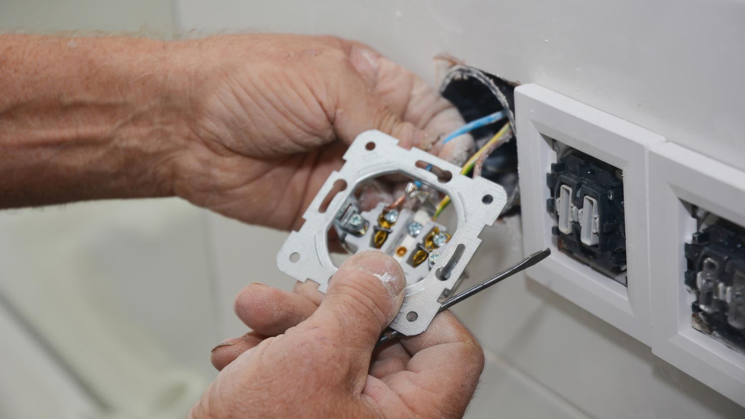 A man inspecting an electrical outlet