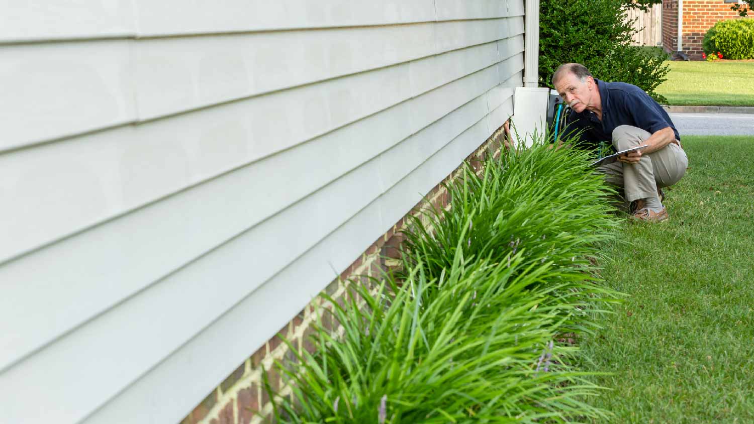 A man inspecting a house’s foundation